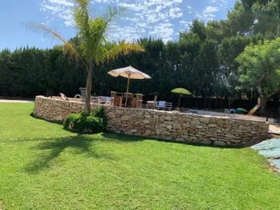 a stone retaining wall with a table and umbrella at Casa Kiosko 3 bedroom chalet with swimming pool in La Eliana