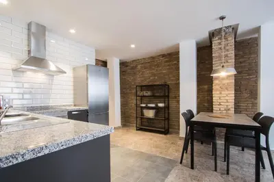 a kitchen with a table with chairs and a refrigerator at Apartamentos La Marina in Valencia
