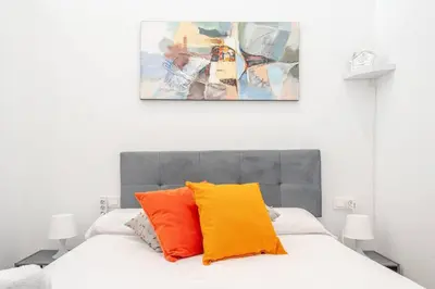 a bedroom with a bed with orange and yellow pillows at Vlc Yako Suite in Valencia