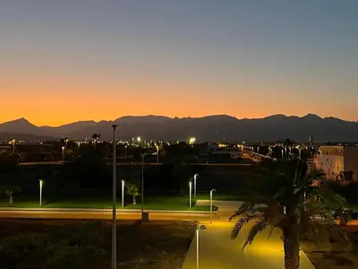 a sunset over a city with a palm tree and mountains at Moncofa Sunset in Moncófar
