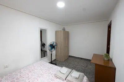 a bedroom with a bed and a desk and a fan at Cómodo apartamento cerca del metro y de la feria Valencia in Paterna