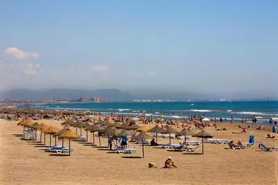 a crowd of people on a beach with umbrellas at Apartamento de diseño a 500 metros de la playa in Valencia