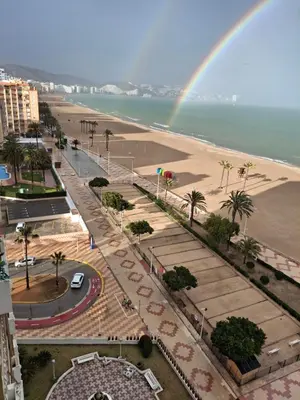 a rainbow over a beach and a street at Arensol Playa de Cullera in Cullera
