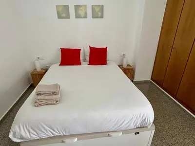 a bedroom with a white bed with red pillows at District Key - Valencia, Playa Patacona in Valencia