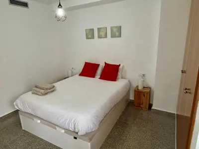 a bedroom with a white bed with red pillows at District Key - Valencia, Playa Patacona in Valencia