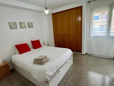 a bedroom with a white bed with red pillows at District Key - Valencia, Playa Patacona in Valencia