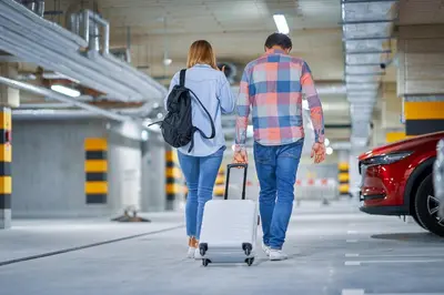 a man and woman walking with a suitcase and a car at Hotel Sercotel Plana Onda in Onda