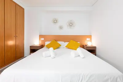 a bedroom with a white bed with two yellow pillows at ApartUP Patacona Iconic I in Valencia