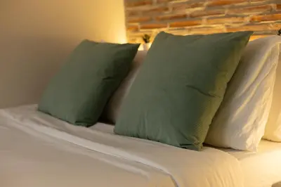 a bed with two green pillows on top of it at Apartamento 4 Pax Vistas Torres de Serrano in Valencia
