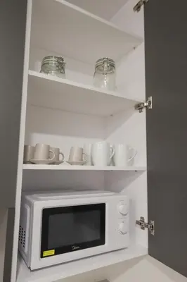 a microwave in a kitchen with cups and saucers on shelves at ADapartments in Valencia