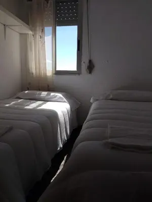 three beds in a room with a window at Reina Beach House in Valencia
