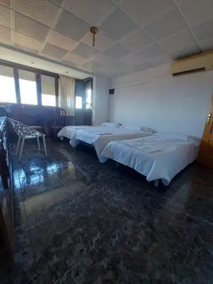 two beds in a large room with two chairs at Reina Beach House in Valencia