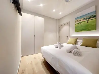 a white bedroom with a large white bed and a painting at Fitness & Spa, Suite Atalanta Valencia in Valencia