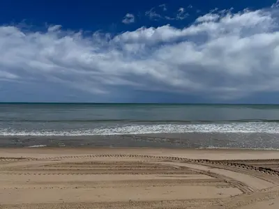 an empty beach with the ocean and clouds in the sky at Brisa de mar in El Perelló