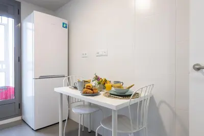 a white kitchen with a white table and chairs at El Cabañal - Familiar in Valencia