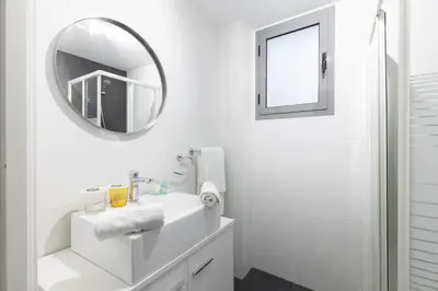 a white bathroom with a mirror and a sink at El Cabañal - Familiar in Valencia