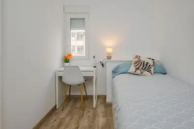 a small bedroom with a bed and a desk at Malva Playa in Valencia