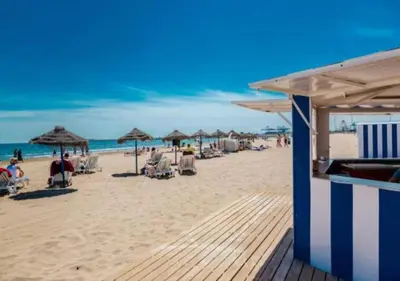 a beach with chairs and umbrellas and the ocean at Exclusivo apartamento a 5 minutos de la playa in Valencia