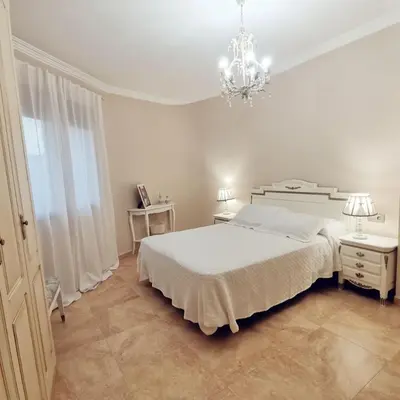 a white bedroom with a large bed and a chandelier at Casa Crispetes in Tales