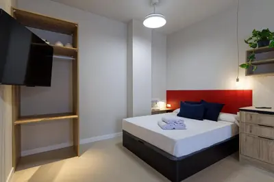 a bedroom with a bed and a flat screen tv at Osito Hub - Colomer in Valencia
