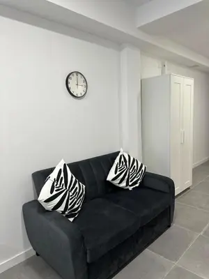a black couch in a room with a clock on the wall at Alojamiento,Hospedaje centrico en valencia in Valencia