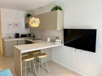 a kitchen with a bar with stools and a tv at Osito Hub - Florista in Valencia