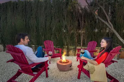 a man and a woman sitting in chairs around a fire at Private Garden Villa near Valencia with Cinema and Gym in La Eliana