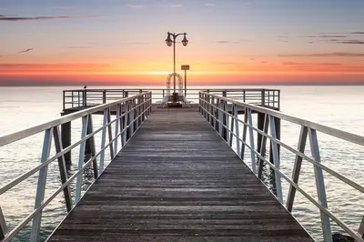 a wooden pier leading to the ocean at sunset at Apartamento playa de chilches in Chilches