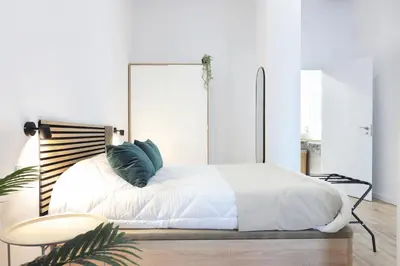 a bedroom with a white bed and a table at Total Valencia Sorolla in Valencia