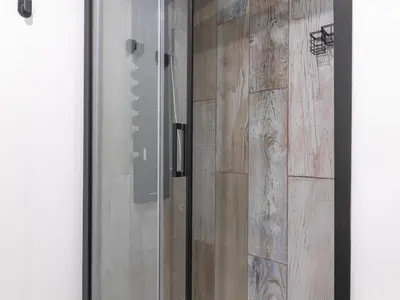 a glass shower door with a wooden wall at Winahost Paterna Palisses in Paterna