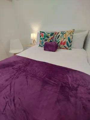 a large bed with a purple blanket on it at New central flat with AC and Wifi in Valencia