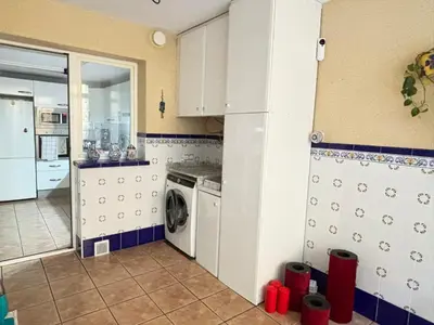 a kitchen with white cabinets and a washer and dryer at Bahia Park Résidence in Cullera