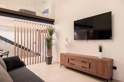 a living room with a couch and a tv on a wall at Aqua Suites Ciudad de las Artes II in Valencia