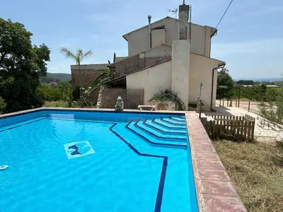 a large blue swimming pool in front of a house at Hort de les Oronetes in Alzira