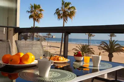 a table with plates of food on a balcony with the beach at Beachfront apartment Cullera Espacio in Cullera