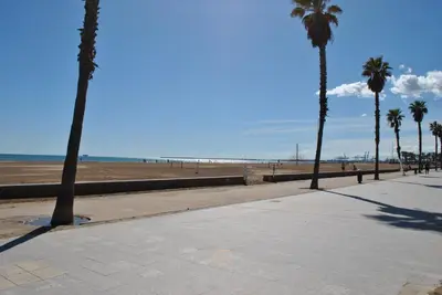 a sidewalk next to a beach with palm trees at RelaxUp Apartment Patacona Beach in Valencia