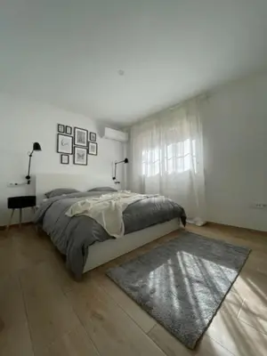 a white bedroom with a bed and a desk at White Lily in Godella