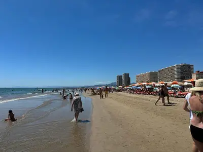 a group of people walking on the beach at La Turia Soleada in Cullera