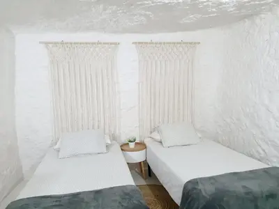 two beds in a room with white walls and curtains at casa cueva a 15 minutos del centro de Valencia in Paterna