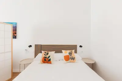 a bedroom with a white bed with orange pillows at Stylish Studio with Easy Access to Valencias Best in Valencia