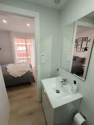 a bathroom with a sink and a mirror and a bed at Cute little apartment in Godella