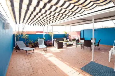 a patio with chairs and tables on a blue wall at Global Vacacional, Ático con barbacoa y gran terraza in Canet de Berenguer