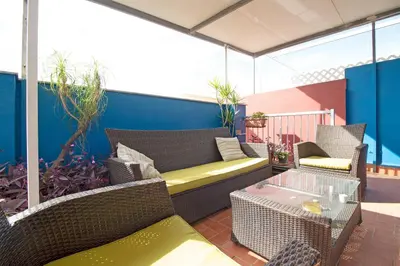 a kitchen with white cabinets and a table and blue chairs at Global Vacacional, Ático con barbacoa y gran terraza in Canet de Berenguer