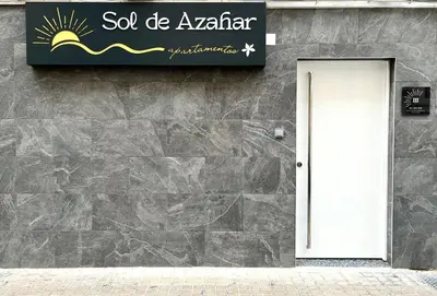 a sign on a stone wall with a white door at Apartamentos Sol de Azahar in Valencia