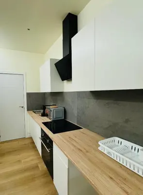 a kitchen with white cabinets and a wooden counter top at Suite Palacio Congresos in Valencia