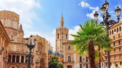 a building with a palm tree and a church at new apartment 4 pax front central station wifi in Valencia