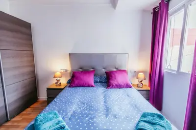 a bedroom with a large bed with purple pillows at Queen Apt, 2min to Beach, Terrace, 3BD, 6PAX in Valencia