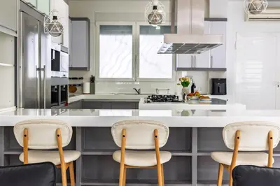 a kitchen with a white counter and three chairs at Casa Familiar 9 Pax, Smart TV, Centro, Playa, Café, AC in Valencia