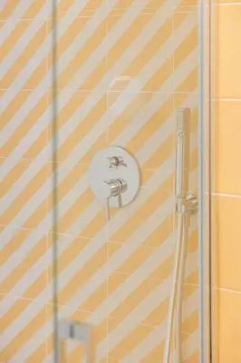 a shower with a shower head on a striped wall at Exclusive beachfront apartment in Valencia