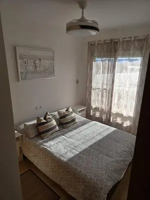 a bedroom with a bed with pillows and a window at Relax en familia junto al mar Les Palmeres in Sueca